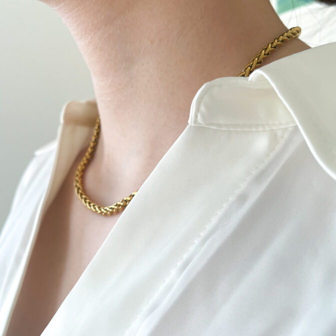 a woman is wearing a gold necklace