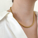 a woman is wearing a gold necklace
