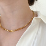 a woman is wearing a gold necklace
