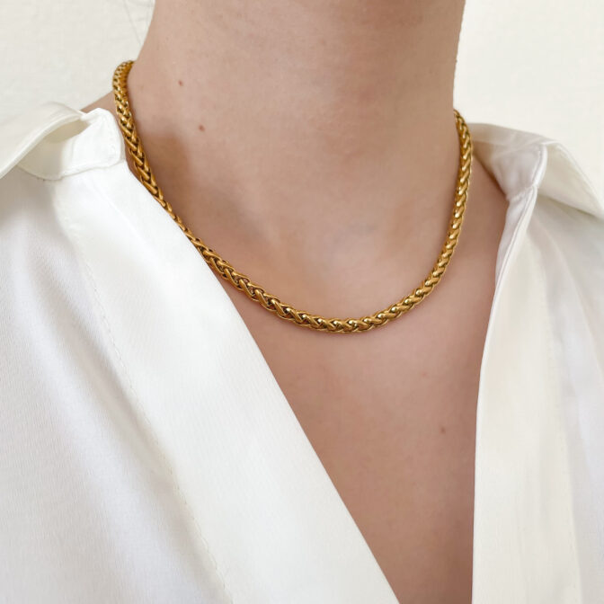 a woman is wearing a gold necklace
