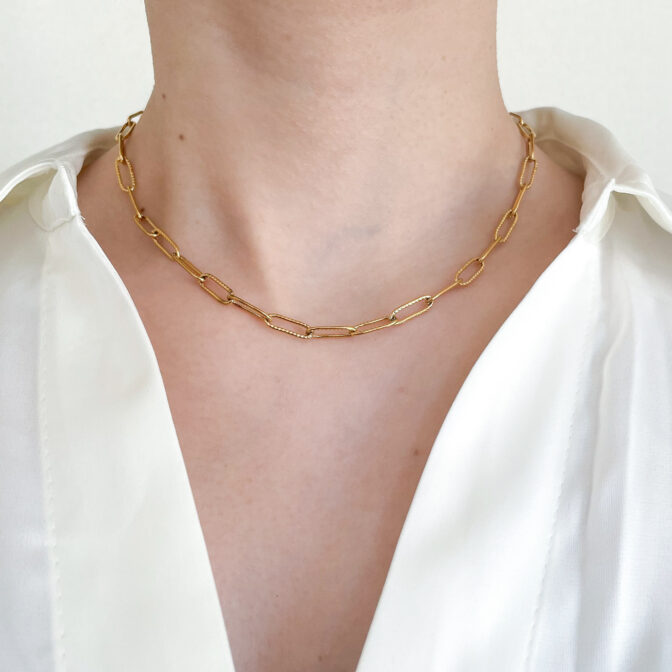 a woman is wearing a gold necklace