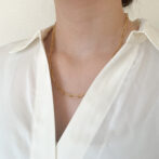 a woman is wearing a gold necklace